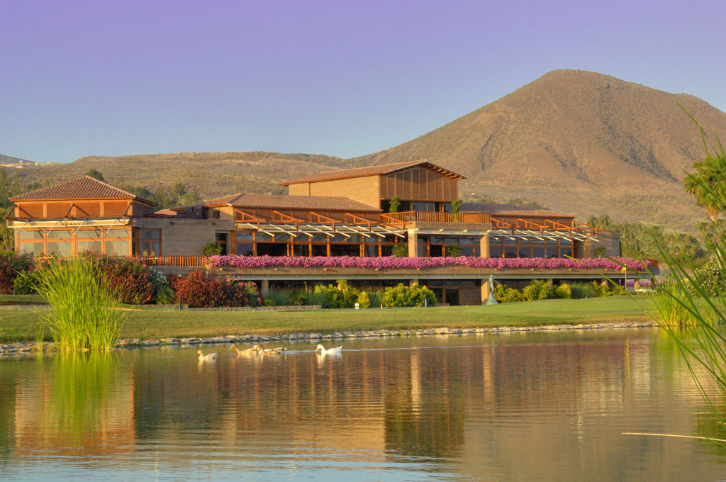 Edificio con flores y lago frente a montaña en Tenerife.