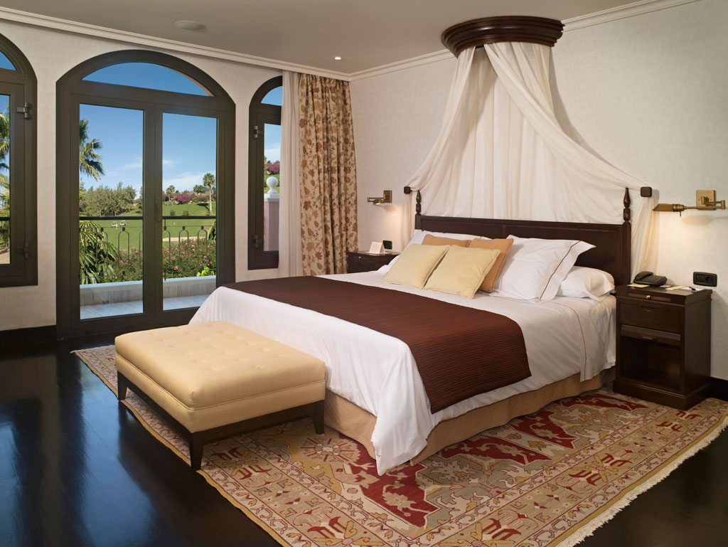 Habitación con cama grande, ventanales y vistas al jardín en hotel de Tenerife.