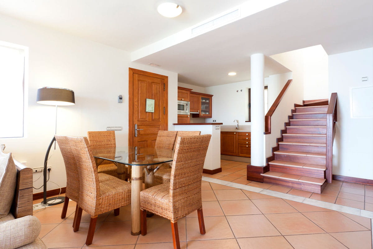 Comedor y escaleras en casa en Tenerife, cocina al fondo.