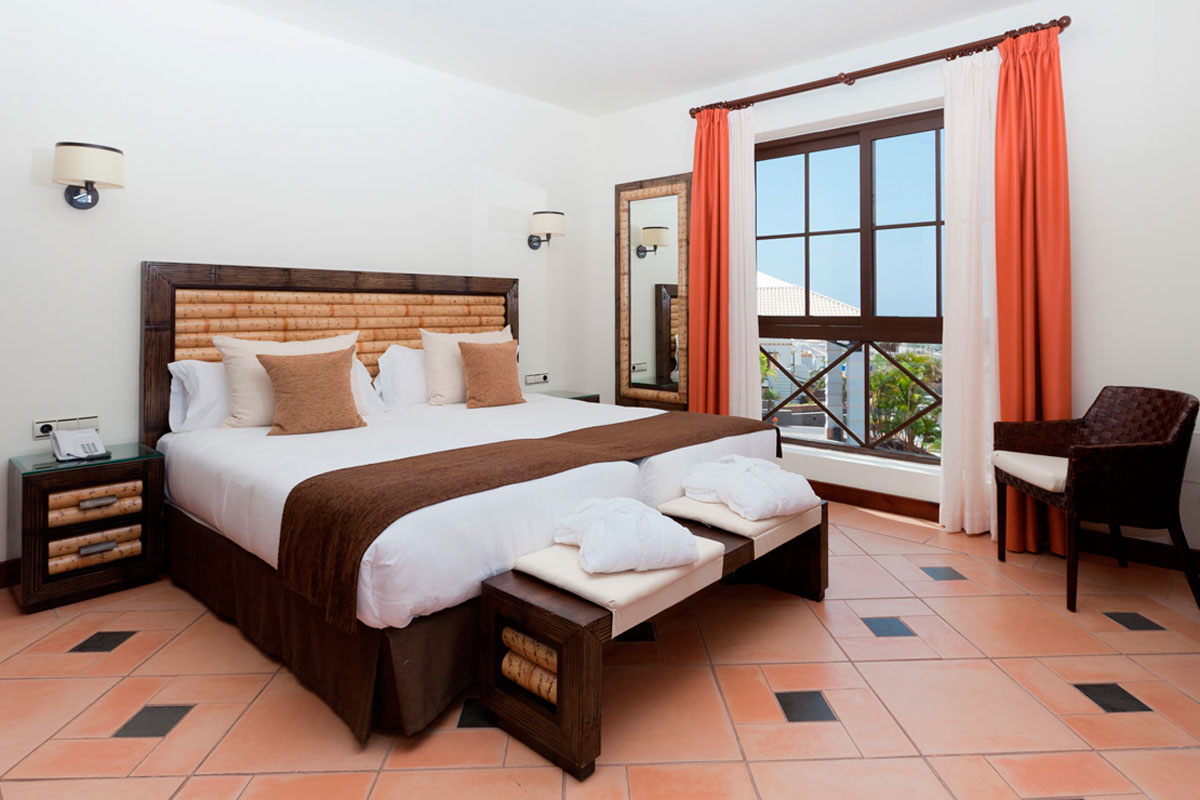 Habitación doble con ventana abierta y cortinas naranjas, Tenerife.
