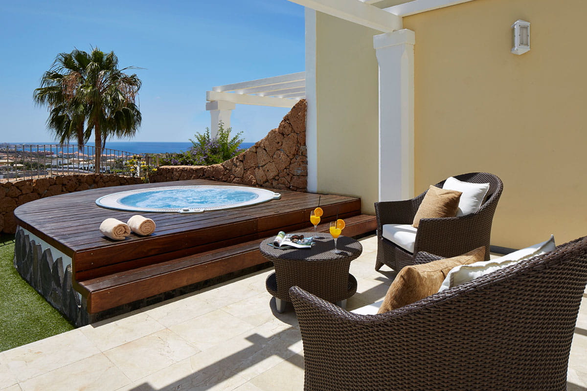 Jacuzzi al aire libre con vista al mar y sillas en una terraza en Tenerife.
