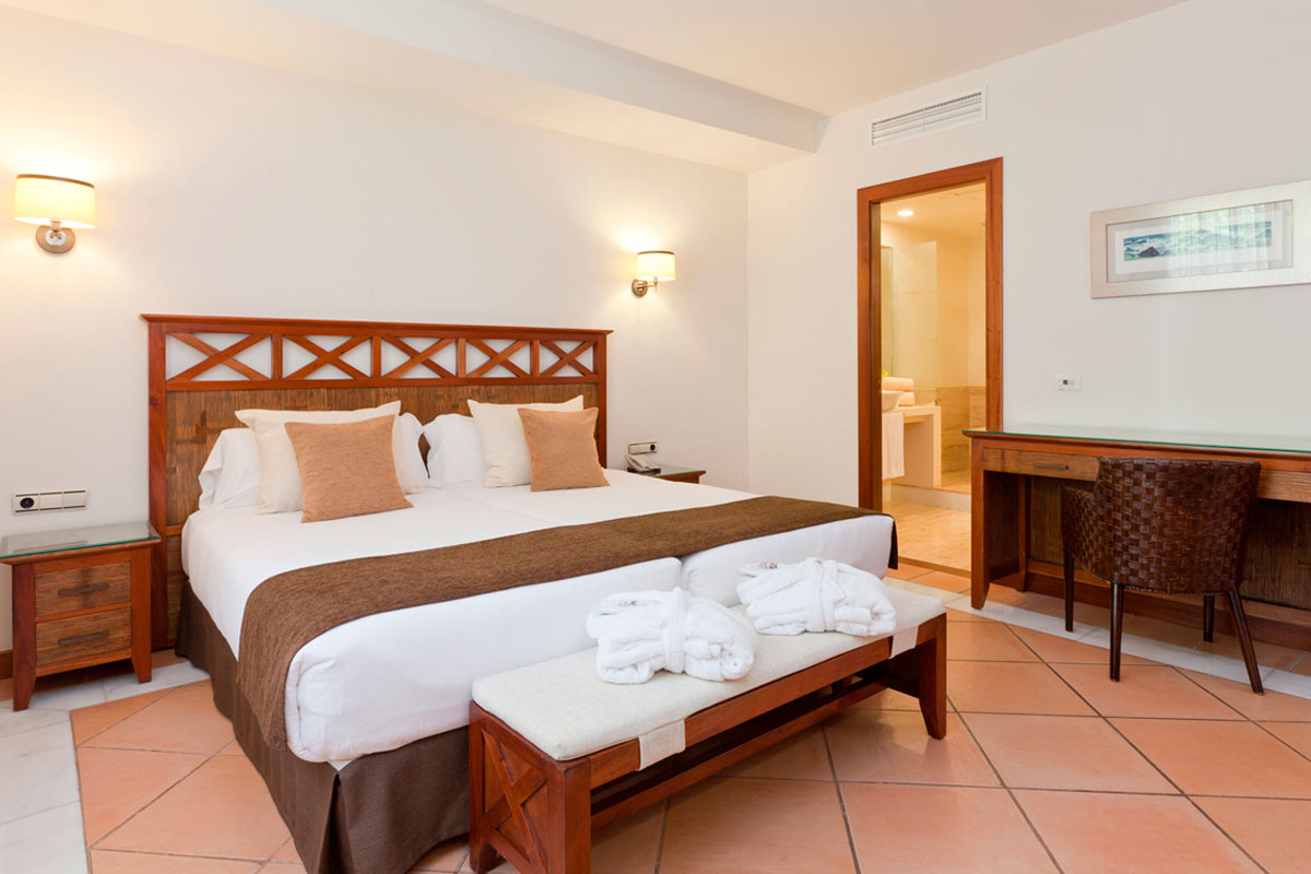 Habitación de hotel con cama doble, tocador y acceso a baño en Tenerife.
