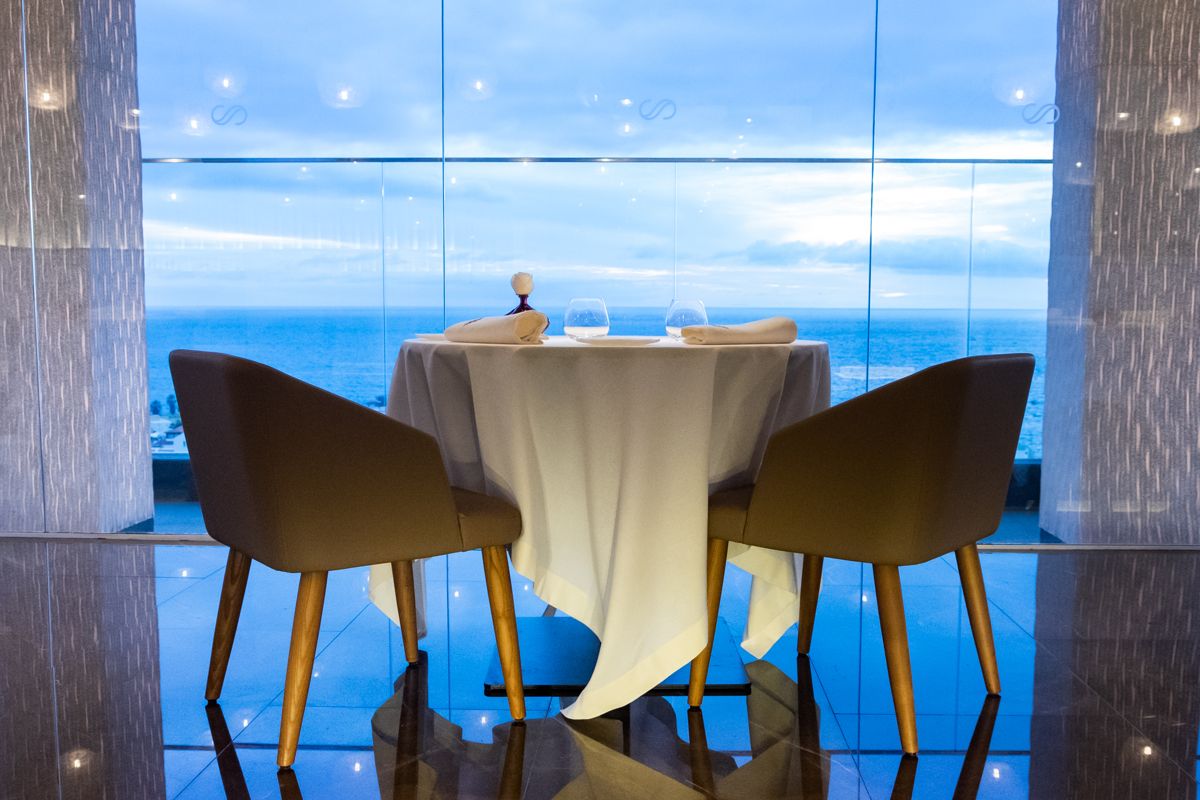 Mesa para dos con vista al mar en Tenerife, cubierta con mantel blanco.