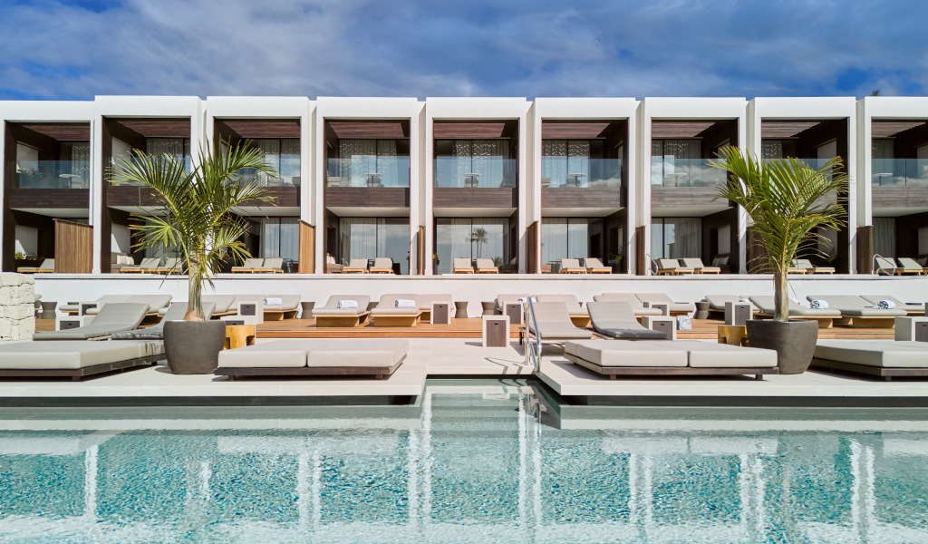Piscina y tumbonas frente a modernas villas en Tenerife.