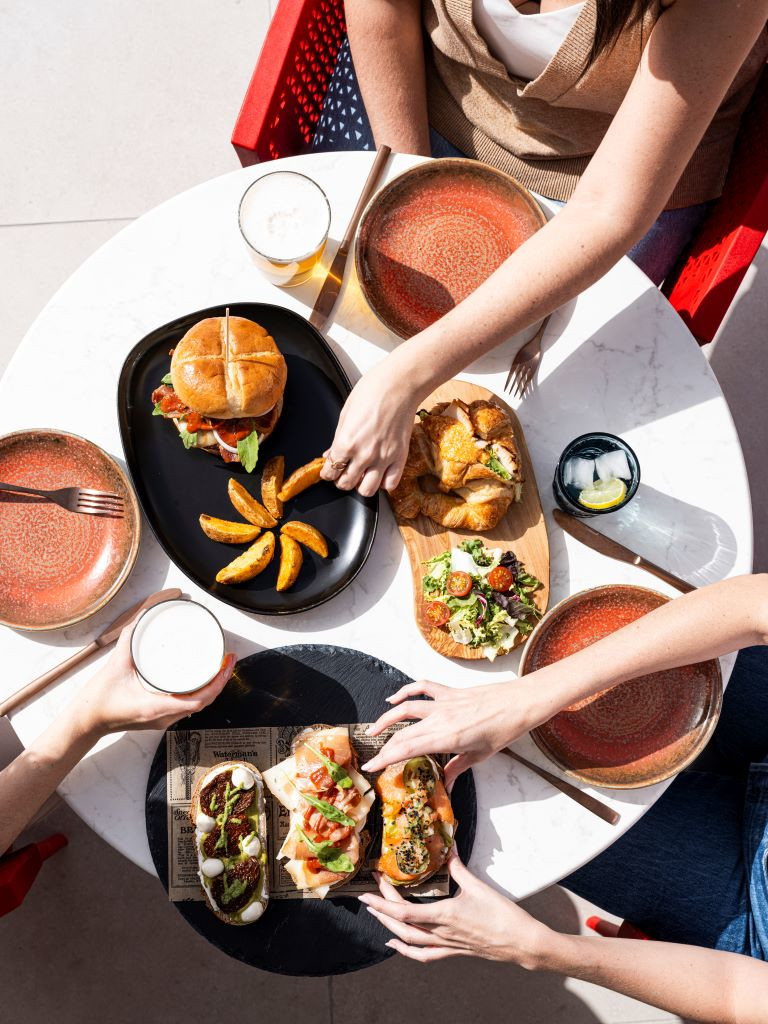 Mesa con hamburguesa, papas fritas, ensalada y bebidas en un restaurante en Tenerife.