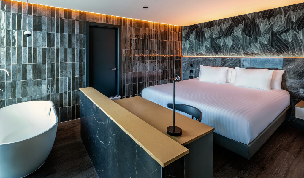 Dormitorio moderno con cama doble y bañera, iluminación cálida en Tenerife.