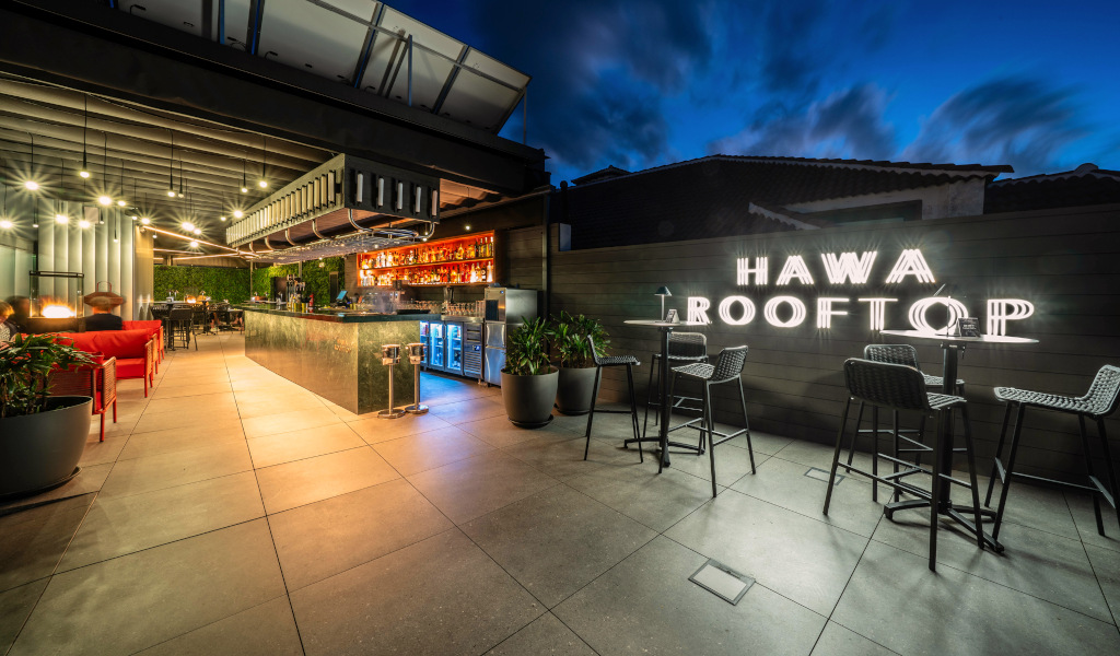 Terraza iluminada del Hawa Rooftop en Tenerife con mesas y bar estilo moderno.