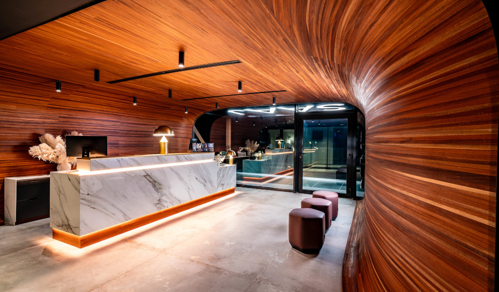 Recepción con mostrador de mármol y pared de madera en hotel de Tenerife.