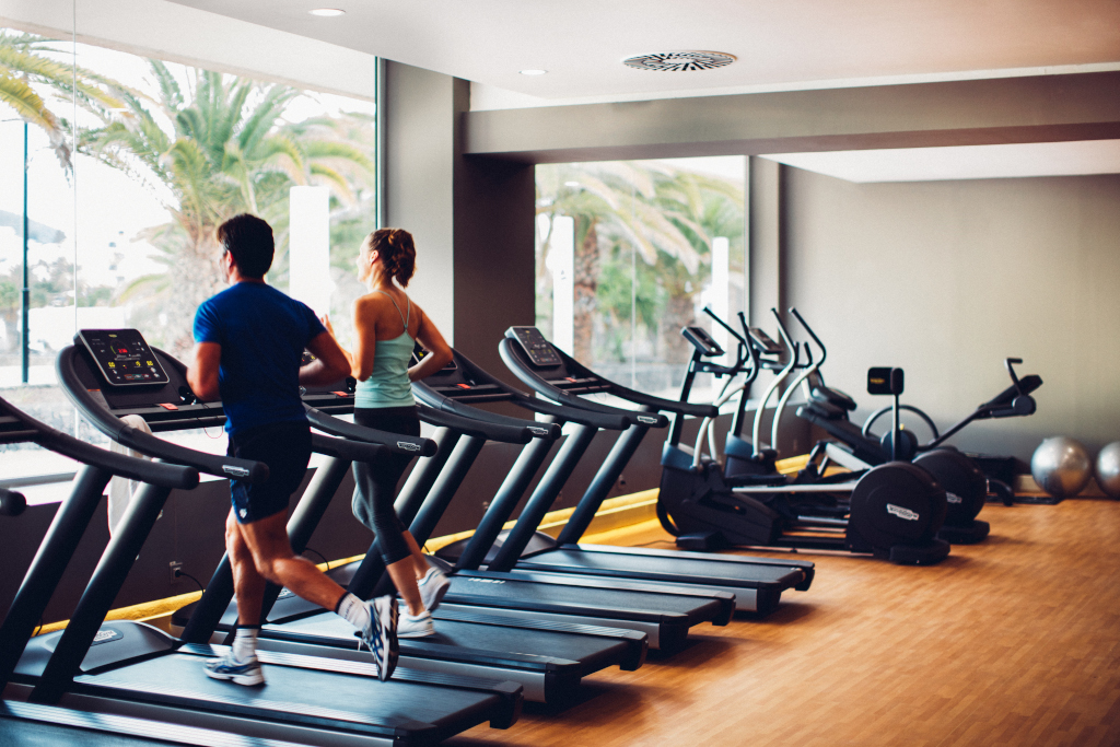 Personas corriendo en cintas de gimnasio en Tenerife, vista interior.