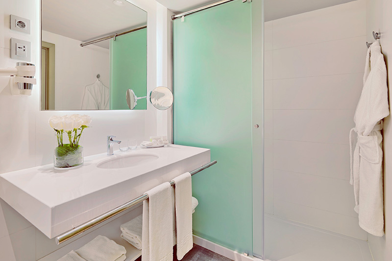 Baño moderno con lavabo, ducha y toallas en hotel de Tenerife.