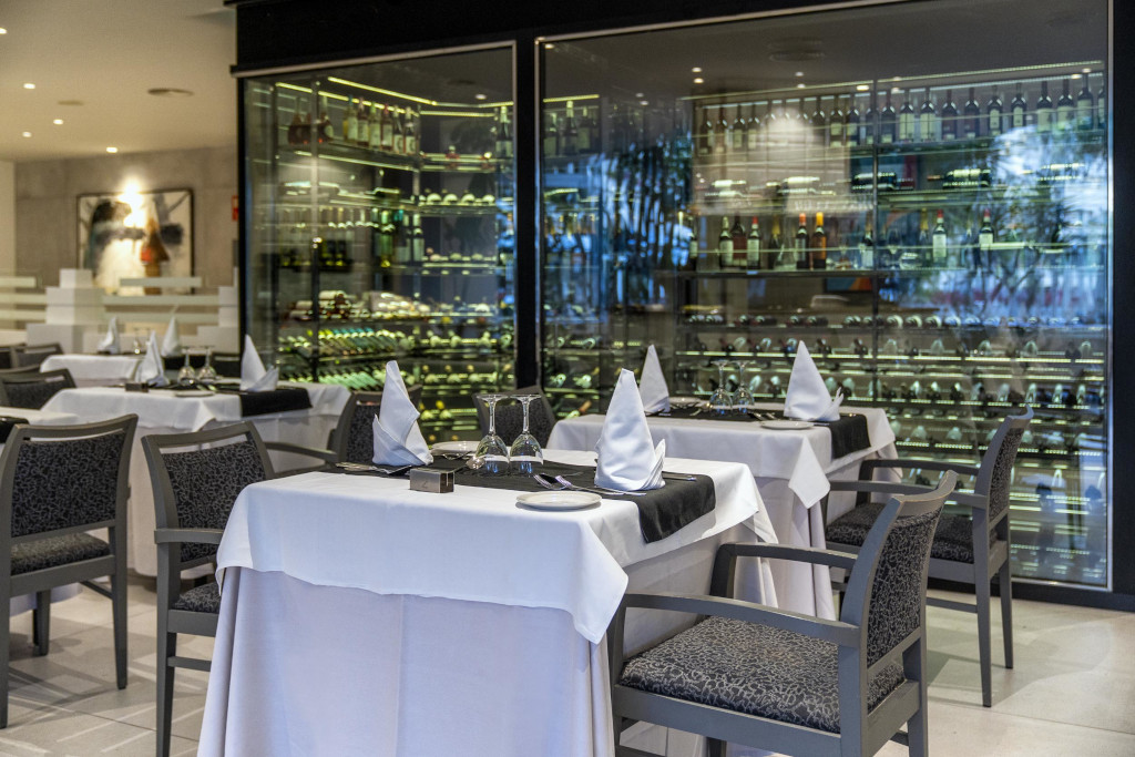 Restaurante elegante en Tenerife con mesas dispuestas y botellas de vino al fondo.