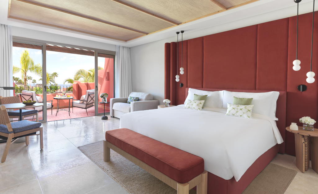 Habitación de hotel en Tenerife con cama doble y terraza con vista a palmeras.