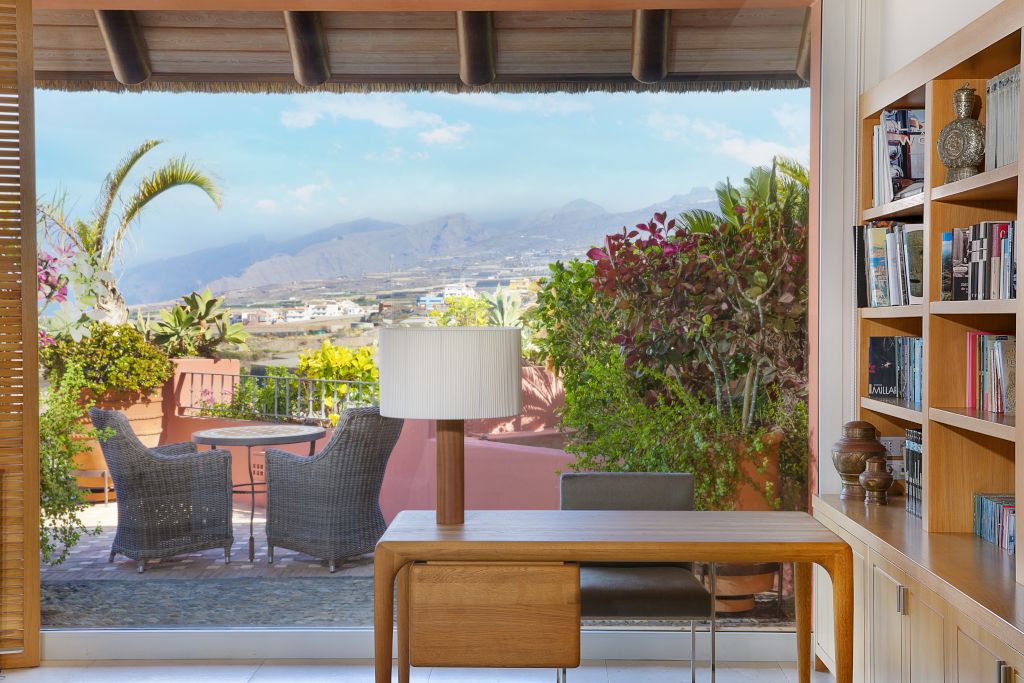 Interior con vista a jardín y montaña desde terraza en Tenerife, con mesa y sillas.