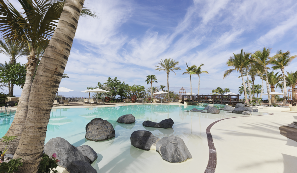 Piscina con palmeras y rocas en un resort en Tenerife.