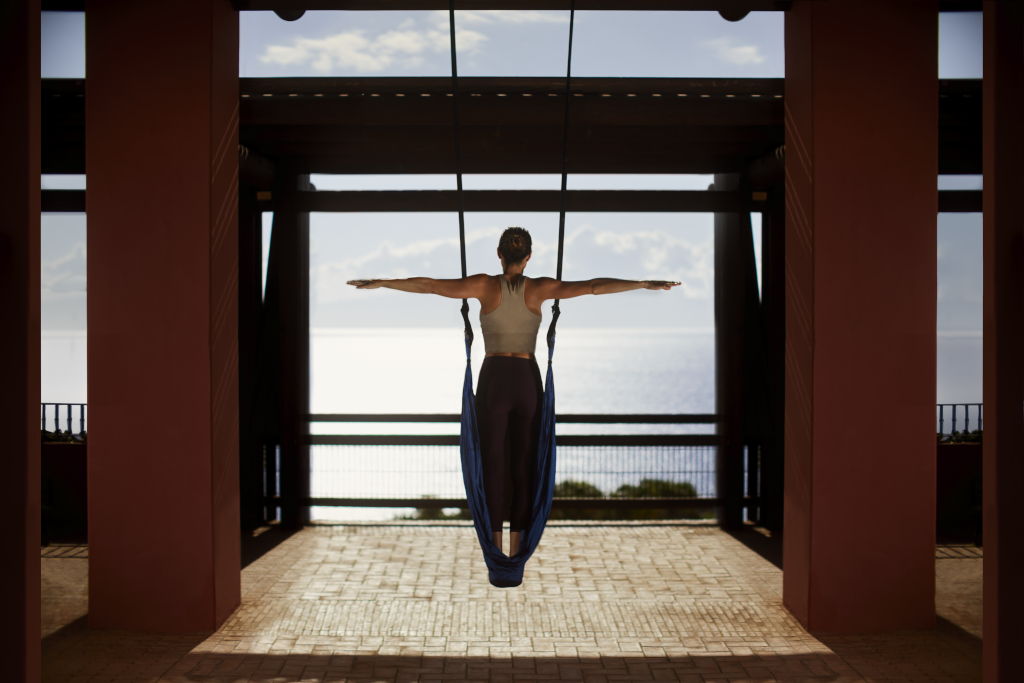 Persona practicando yoga aéreo frente al mar en Tenerife.