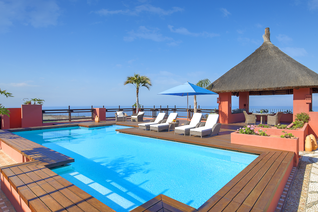 Piscina con sombrillas y sillas junto al océano en Tenerife.