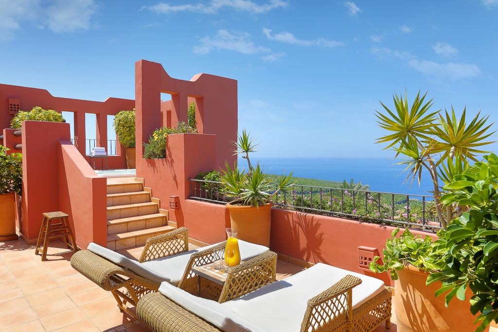 Terraza con vistas al mar en Tenerife, con tumbonas y plantas.
