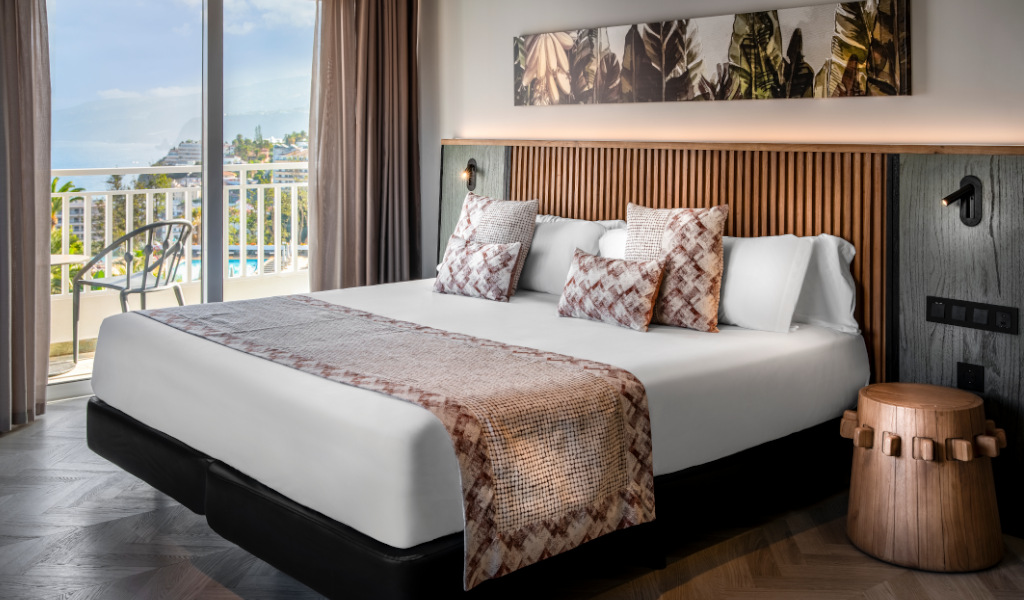 Habitación con cama doble, vista al mar y decoración vegetal en Tenerife.