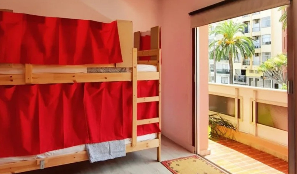 Literas con cortinas rojas y vista a una terraza en Tenerife.