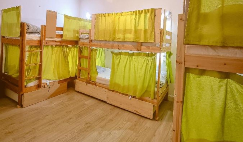 Literas de madera con cortinas verdes en un dormitorio compartido en Tenerife.