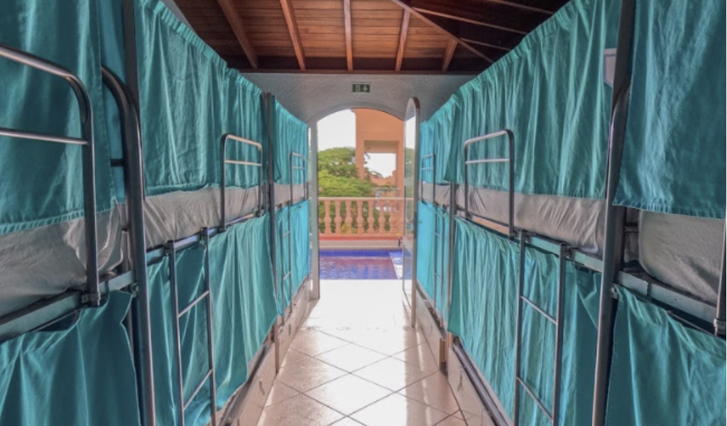 Literas en un pasillo con cortinas verdes en un hostal en Tenerife.