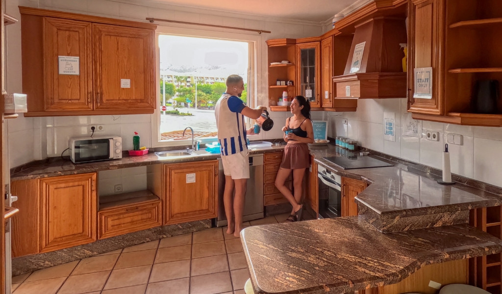 Cocina en Tenerife con dos personas preparando café junto a la ventana.