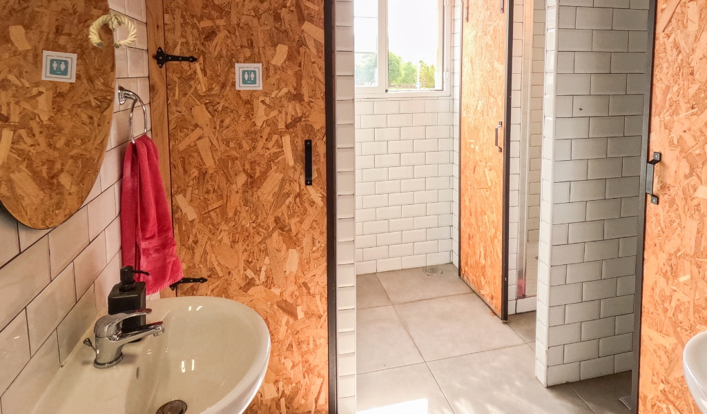 Baño con lavabo, espejo, toalla rosa y puertas de madera en Tenerife.