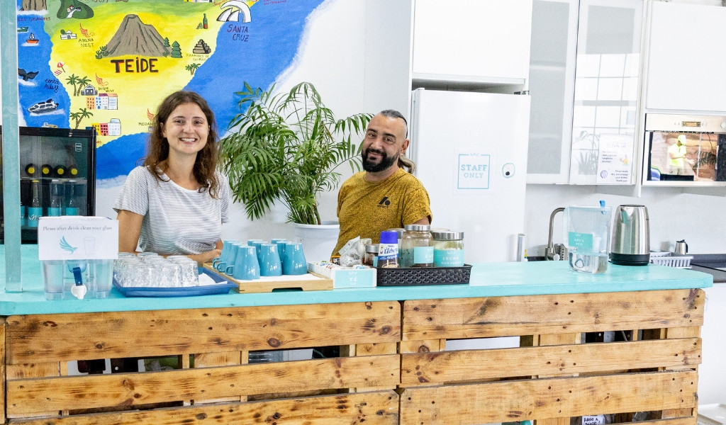 Persona sonriendo detrás de barra con mapa de Tenerife en fondo.