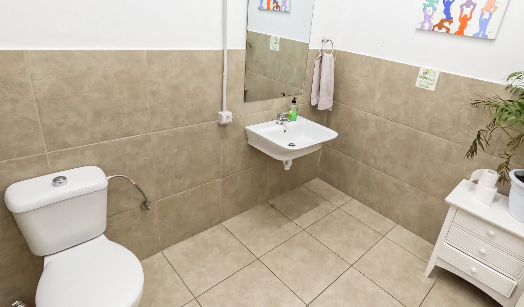 Baño con inodoro, lavabo, espejo y planta decorativa en Tenerife.