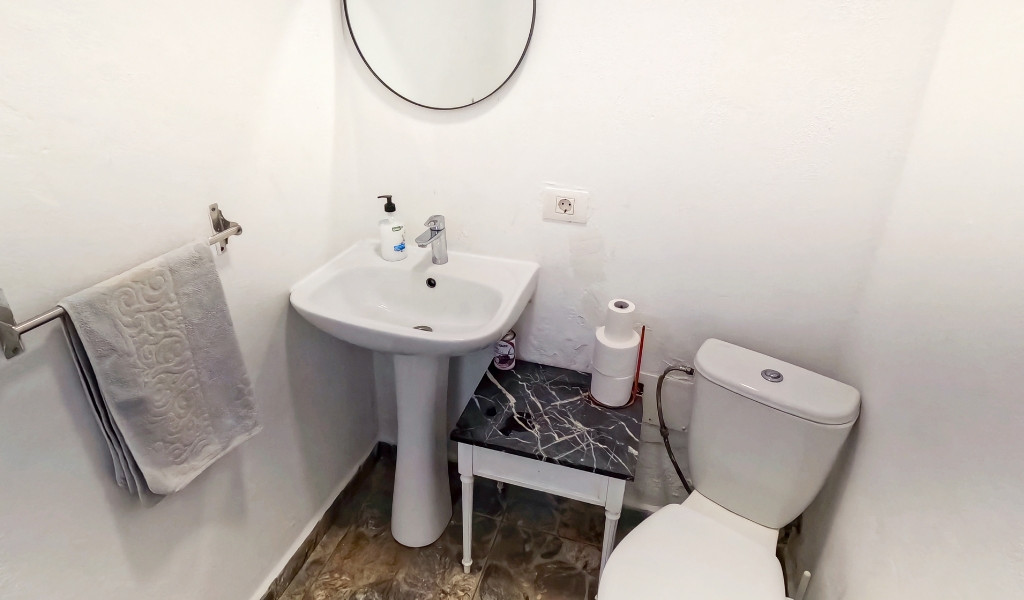 Baño pequeño con lavabo, espejo redondo y un inodoro en Tenerife.