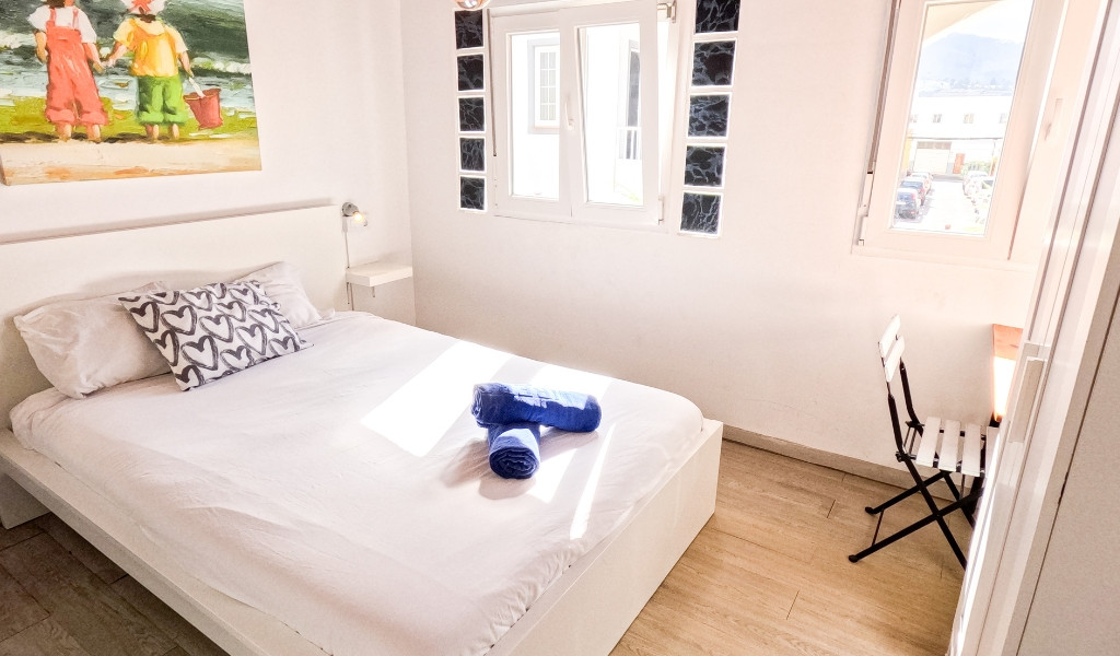 Habitación con cama doble, ventana, silla y cuadro en la pared en Santa Cruz de Tenerife.