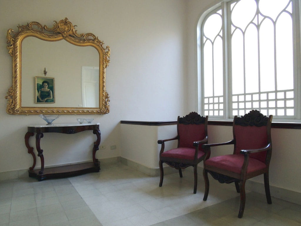 Espejo dorado, cuadro y sillas en una sala iluminada en Tenerife.