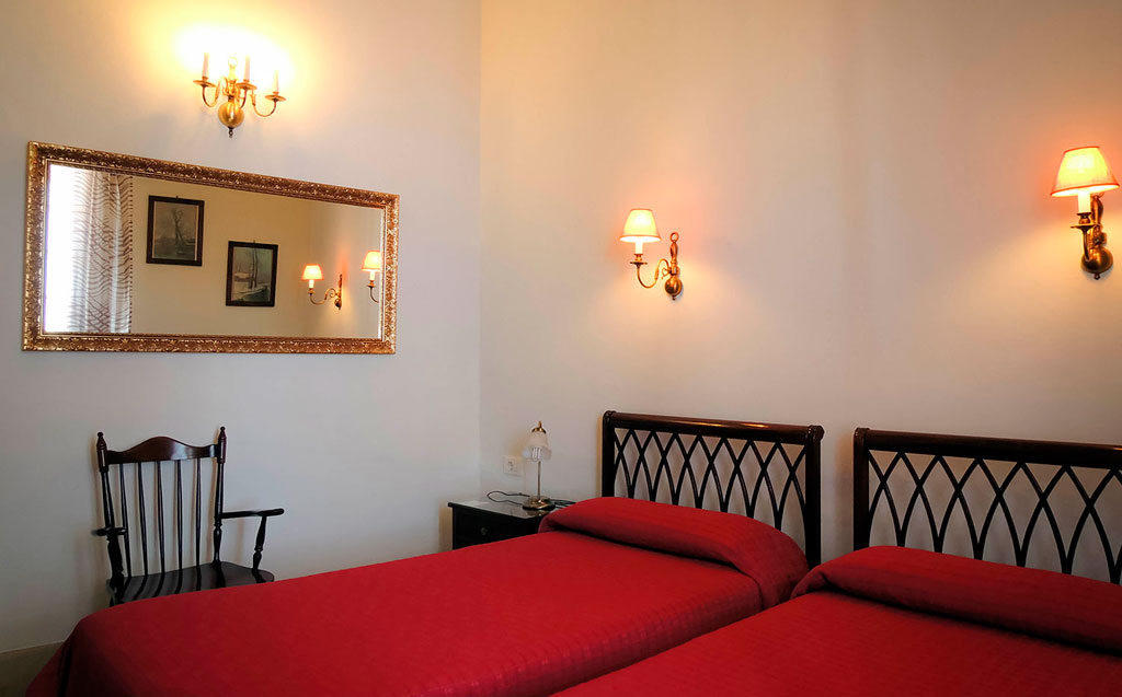 Dos camas con sábanas rojas en habitación iluminada, Puerto de la Cruz.