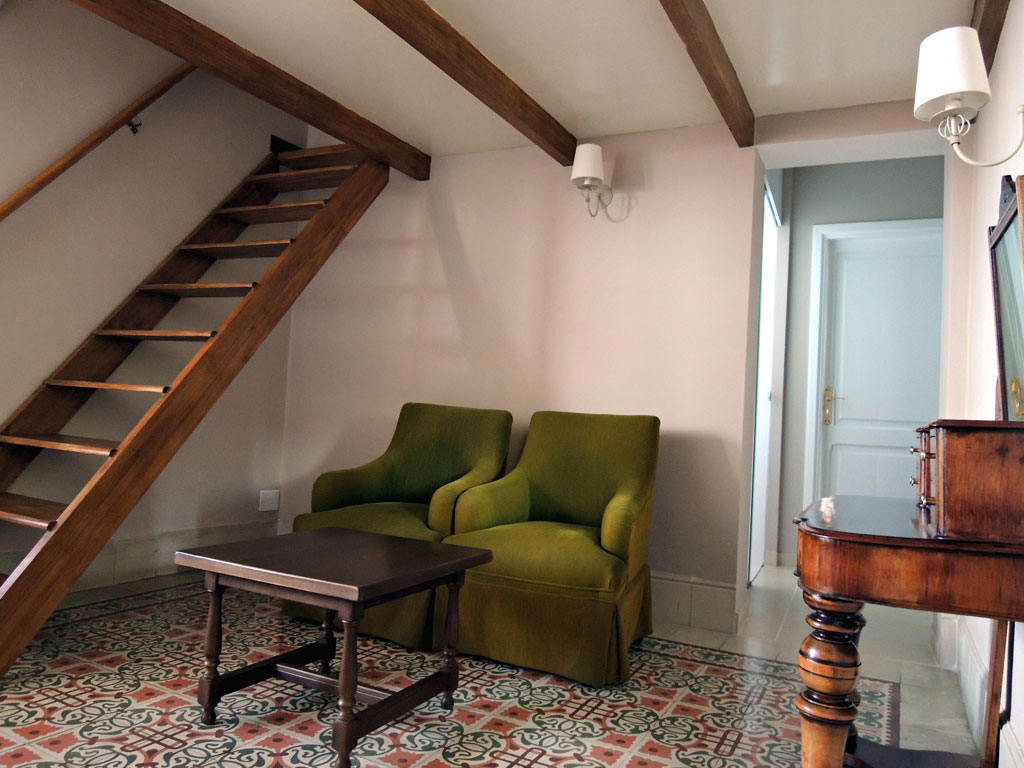 Sala de estar con sillas verdes, mesa de madera y escalera en Tenerife.