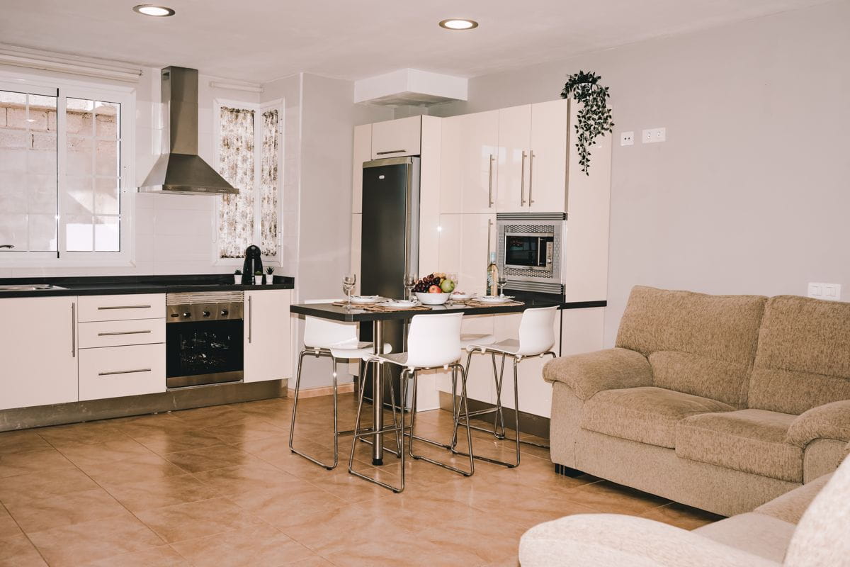 Cocina moderna con sala de estar, mesa y sofá en un apartamento en Tenerife.