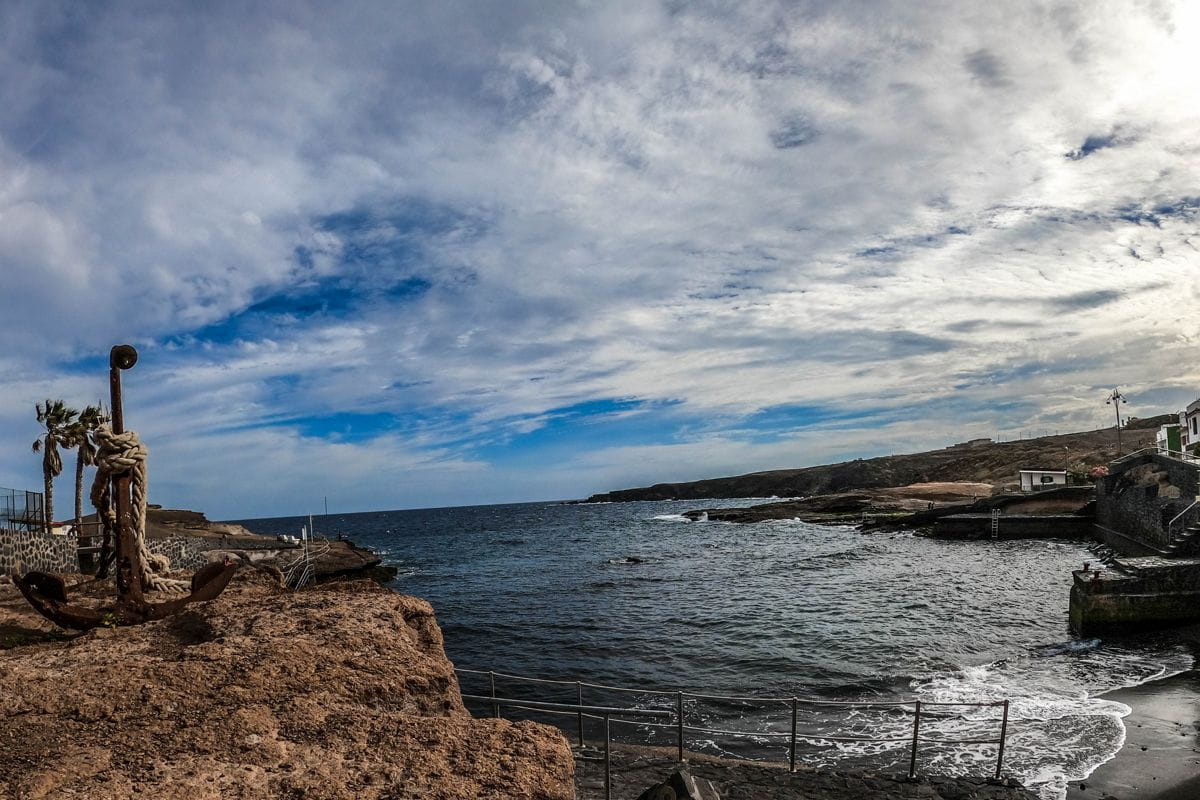 Costa rocosa con ancla y mar en Tajao, Tenerife, bajo un cielo nublado.