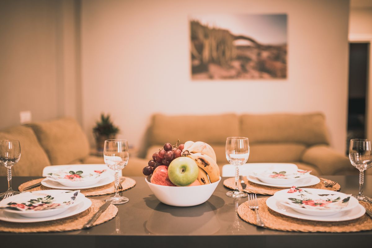 Mesa con platos decorativos y centro de mesa con frutas en un salón de Tenerife.