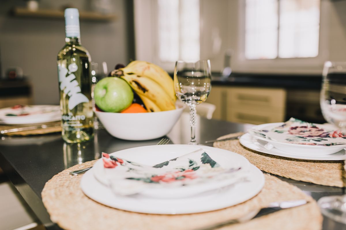 Botella de vino blanco y frutero con plátanos y manzana en cocina de Tenerife.