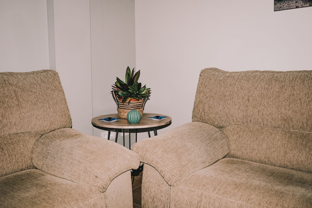 Sofás beige en sala con mesa central y planta en Tenerife.