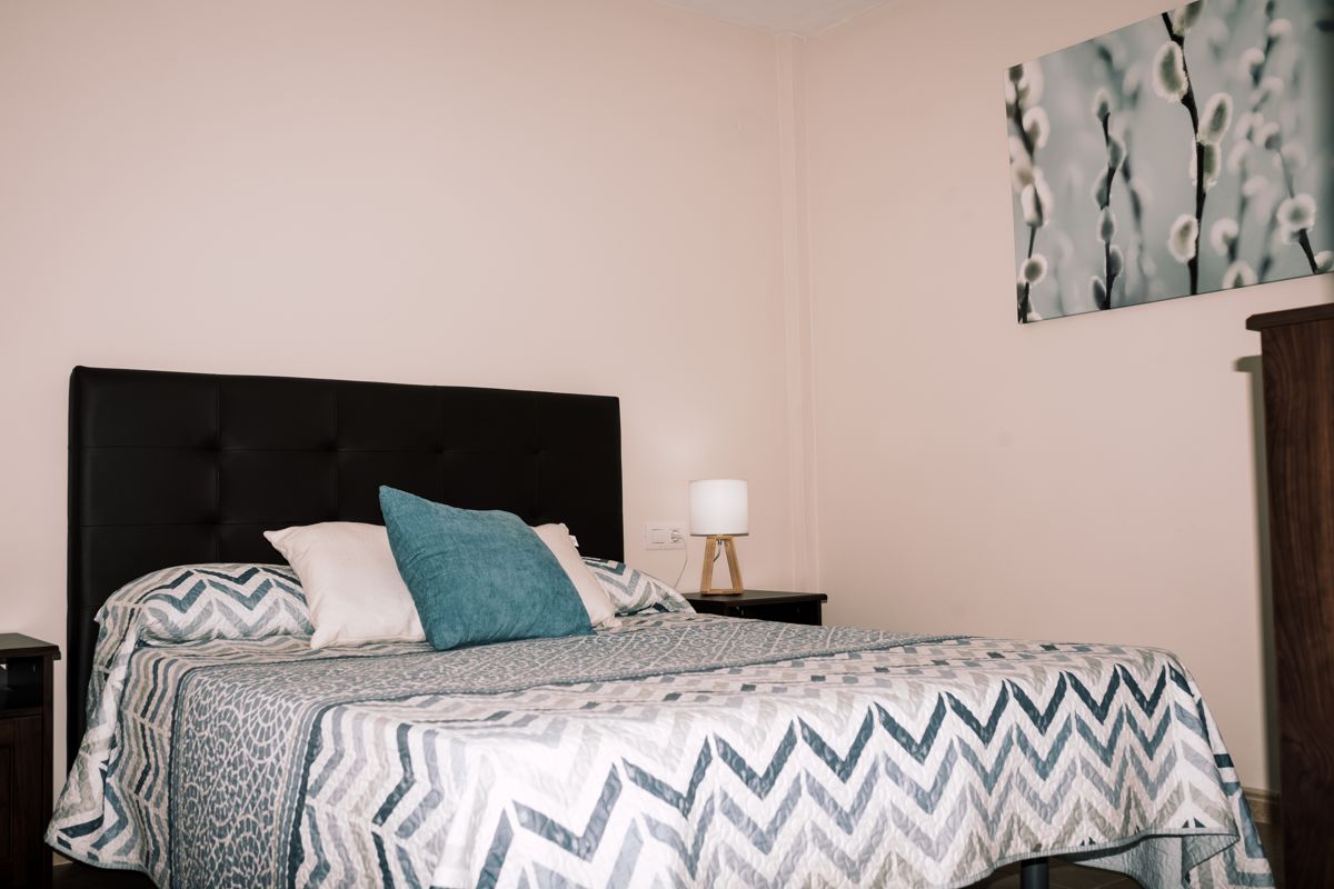 Habitación con cama de doble almohada y lámpara de mesa en esquina en Tenerife.