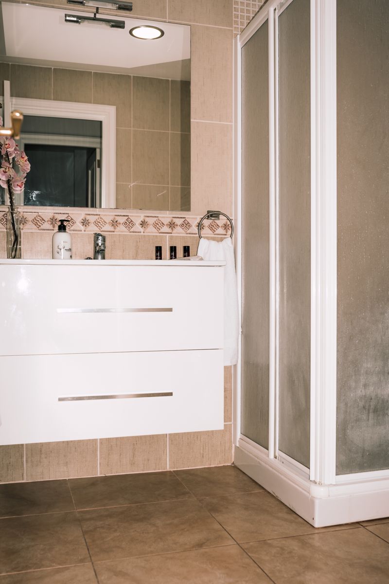 Baño moderno con lavabo blanco y ducha en Tenerife.