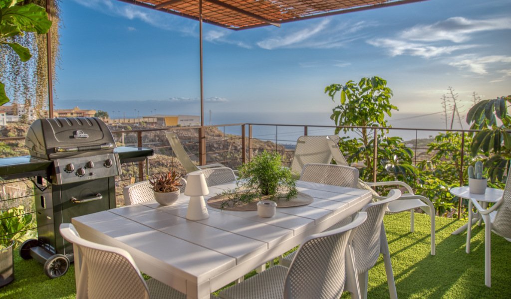 Terraza con mesa y sillas blancas, vista al mar y barbacoa en Tenerife.