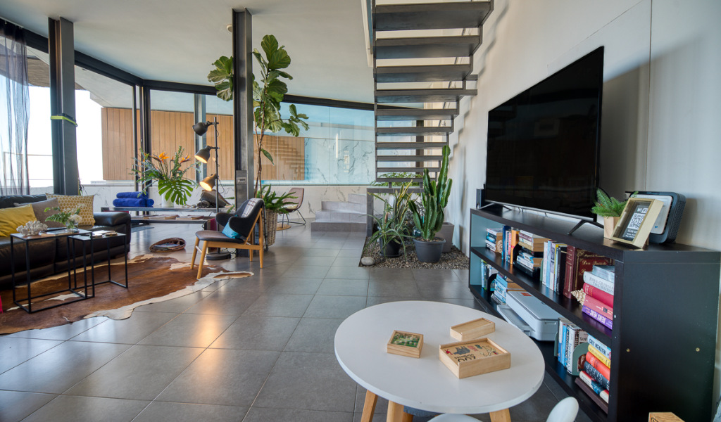Sala de estar moderna en Tenerife con escaleras y televisor grande.