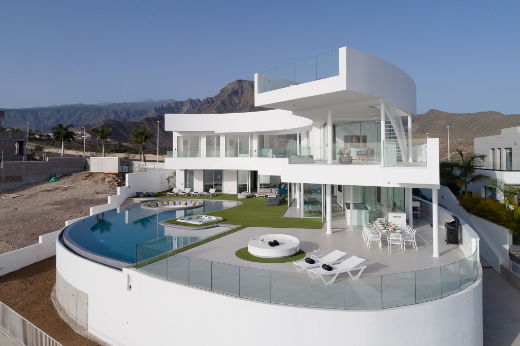 Casa moderna con piscina y terraza en Tenerife, rodeada de montañas y palmeras.