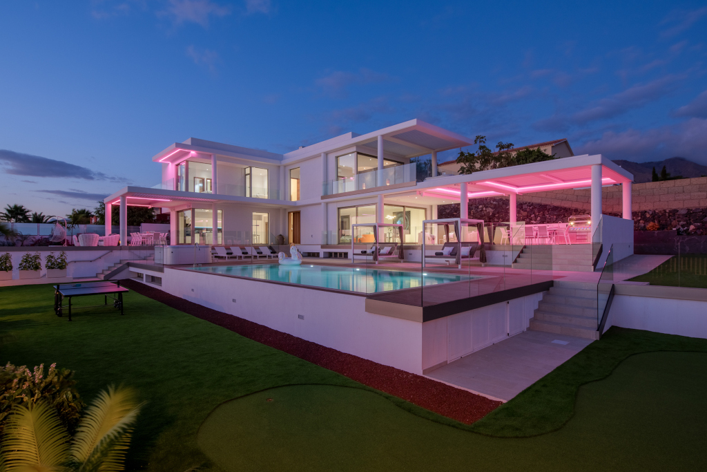 Casa moderna iluminada al anochecer con piscina en Tenerife.