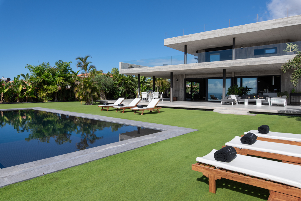 Piscina y tumbonas en el jardín de una casa moderna en Tenerife.
