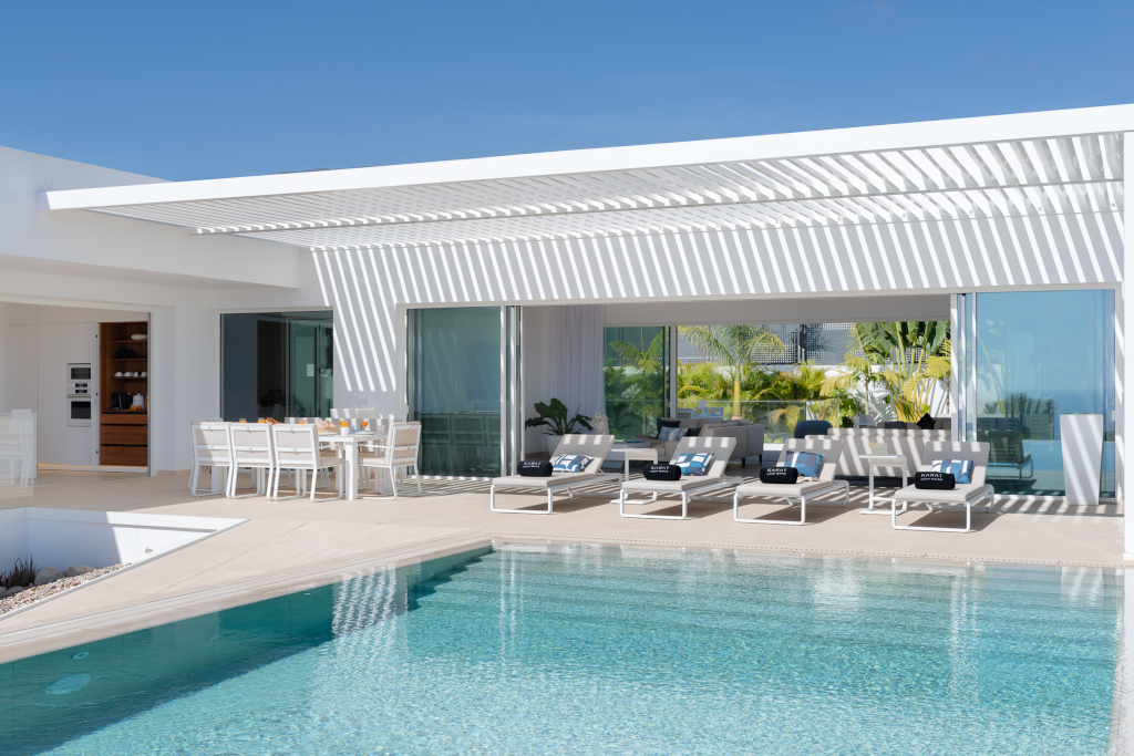 Terraza moderna con piscina, mesas y tumbonas en una villa en Tenerife.