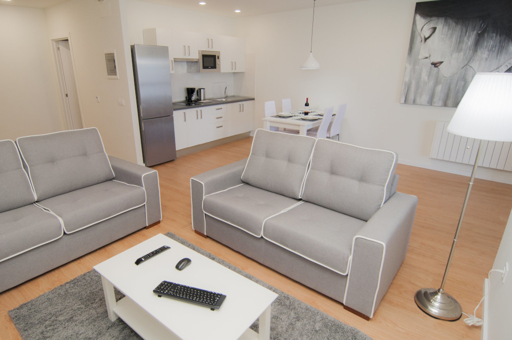 Sala de estar con sillones grises, mesa de comedor y cocina en apartamento Tenerife.