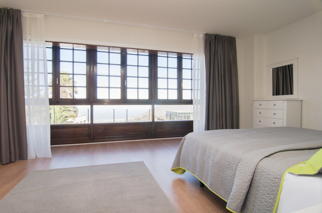 Habitación con cama, ventanas grandes y vistas al mar en Tenerife.