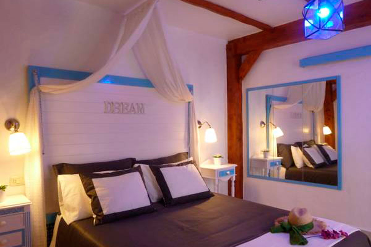 Dormitorio con cama doble, cabecero DREAM, lámparas y espejo en Tenerife.